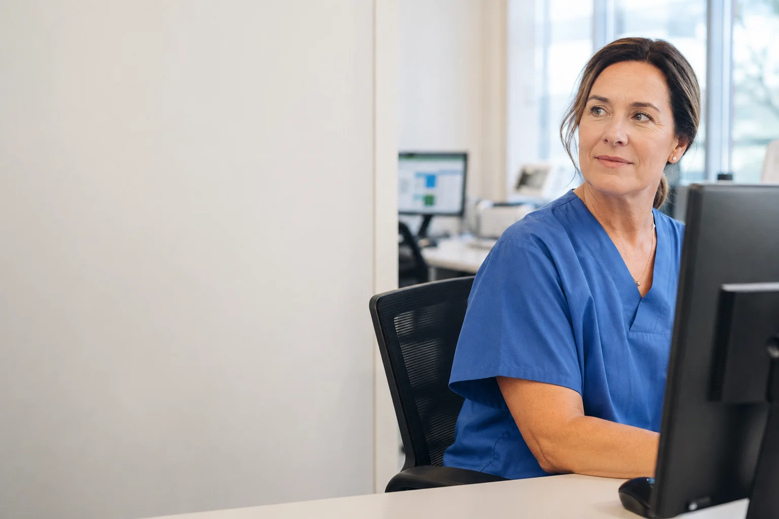 Healthcare professional turning her attention from the computer toward a person